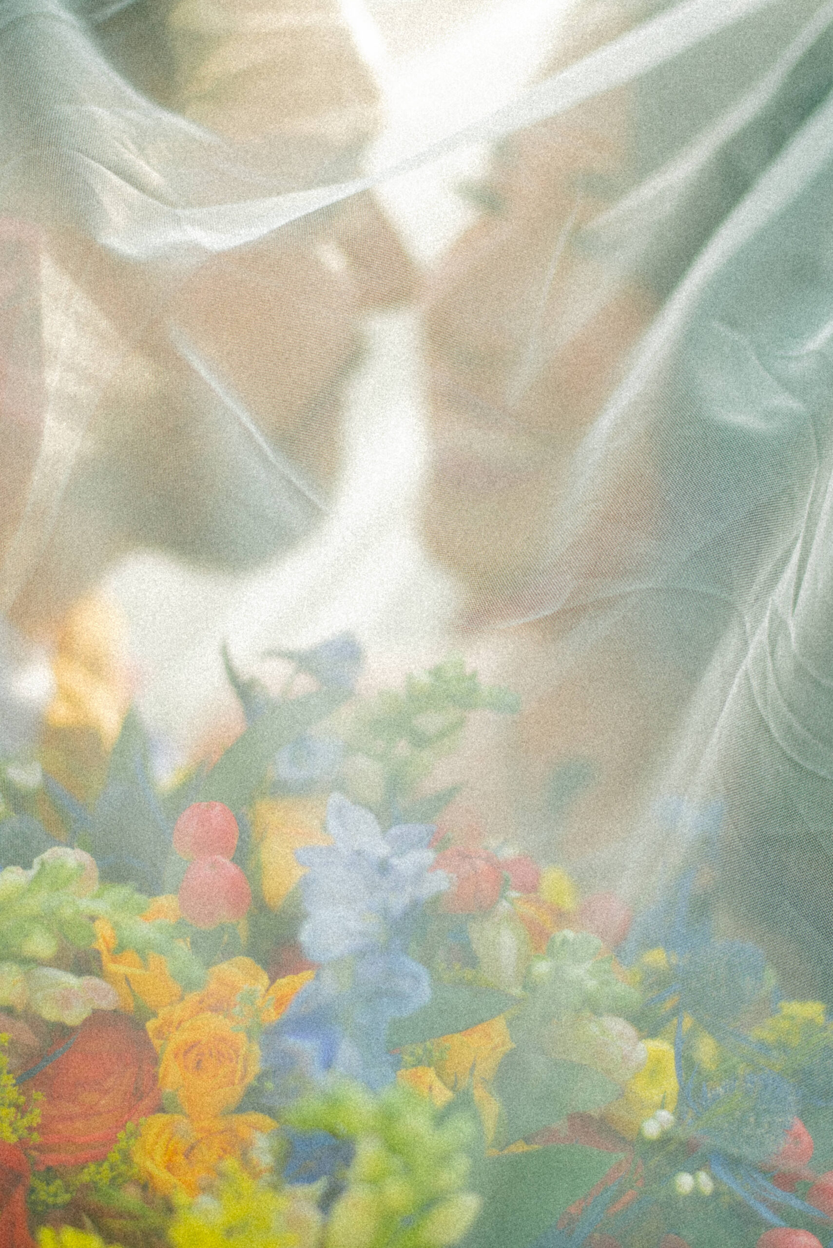 Romantic wedding couple under a flowing veil, sharing an intimate moment of love and connection