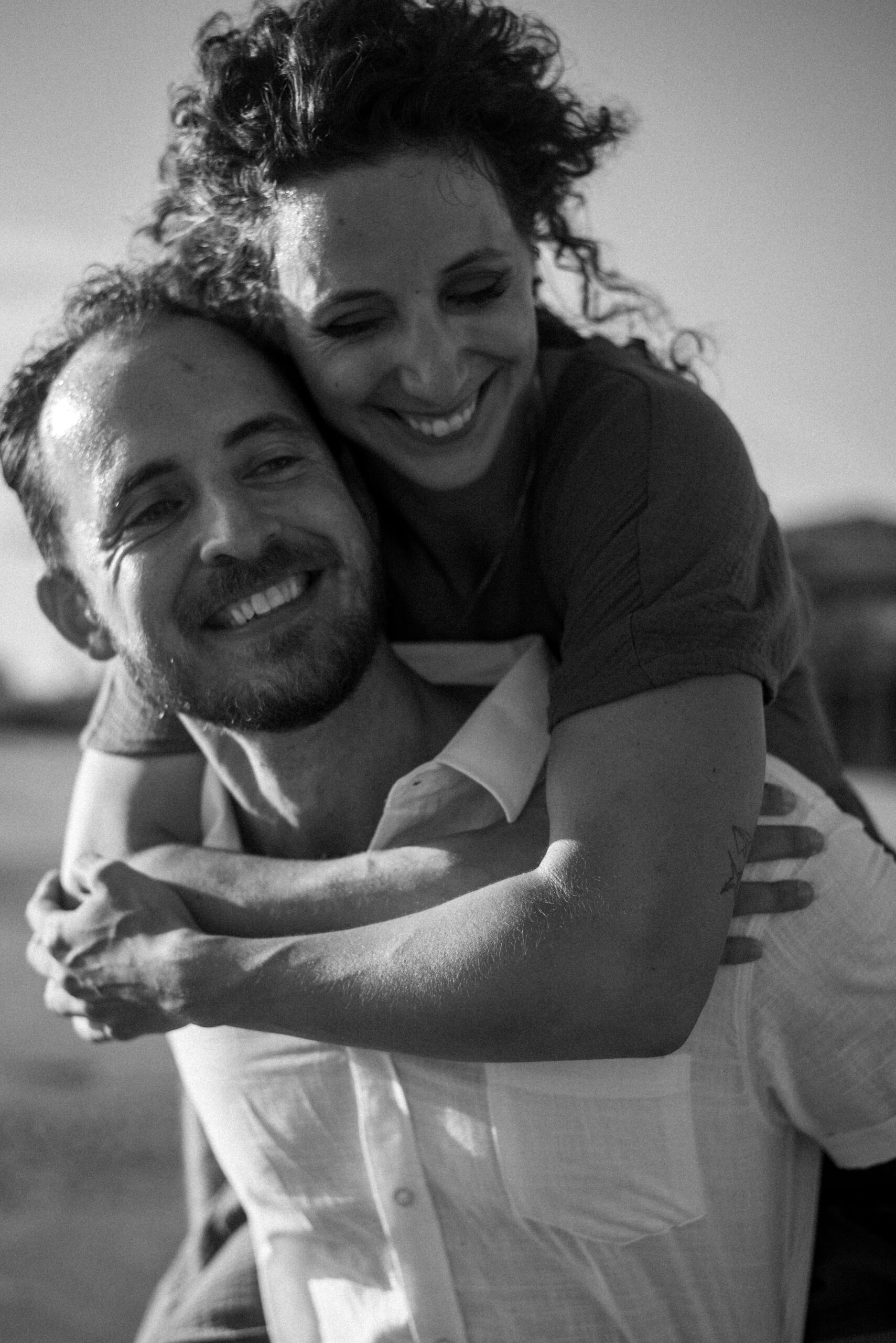 Black and white engagement photo of a couple walking on the beach in Galveston, Texas, captured in a timeless and romantic style.