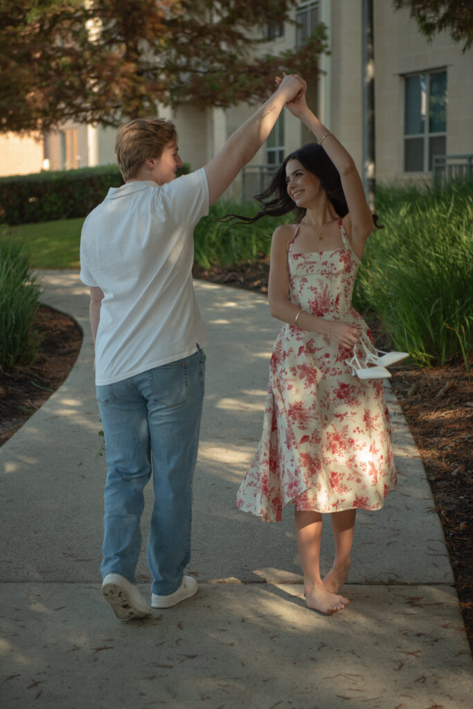 Couple dancing barefoot on a shaded pathway after a romantic lakeside proposal.