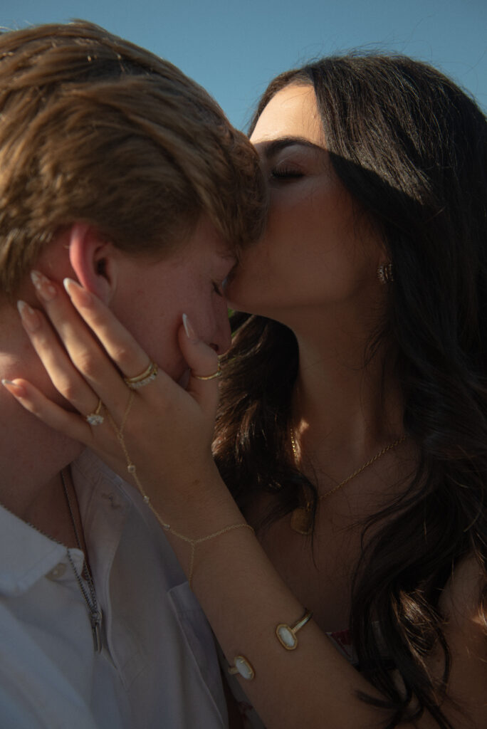 Intimate close-up of couple sharing a forehead kiss after a romantic lakeside proposal