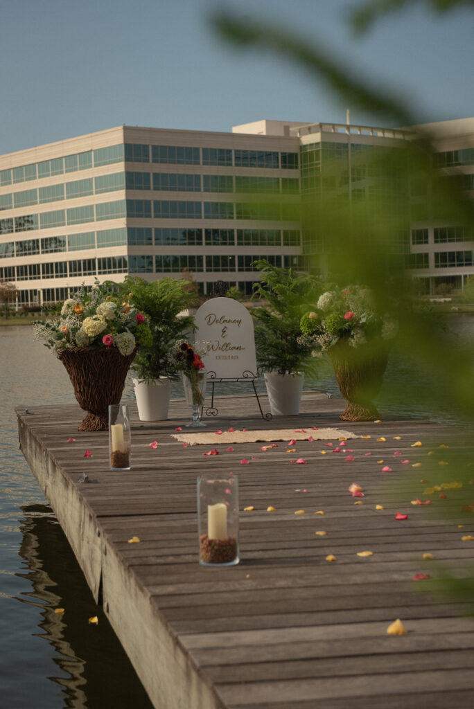 Romantic dockside proposal setup at Lake Woodlands with florals, candles, and a personalized sign under sunny Texas skies