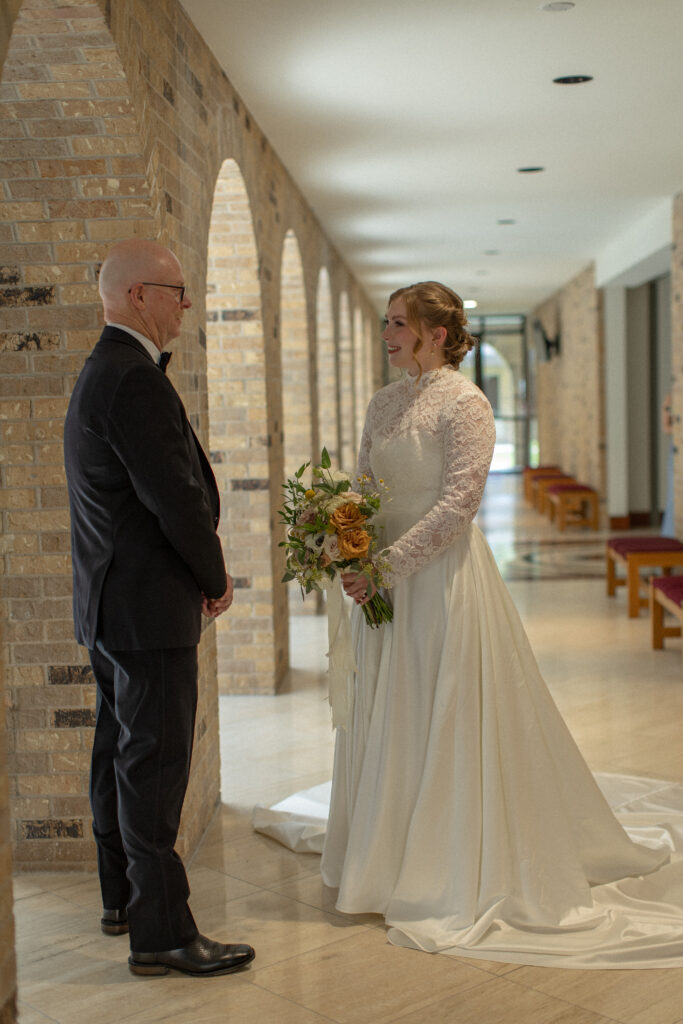 A father smiles warmly during a first look moment with his daughter on her wedding day.