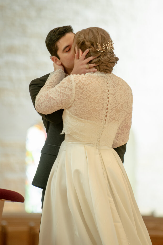 A bride and groom share their first kiss during their wedding ceremony inside the church.