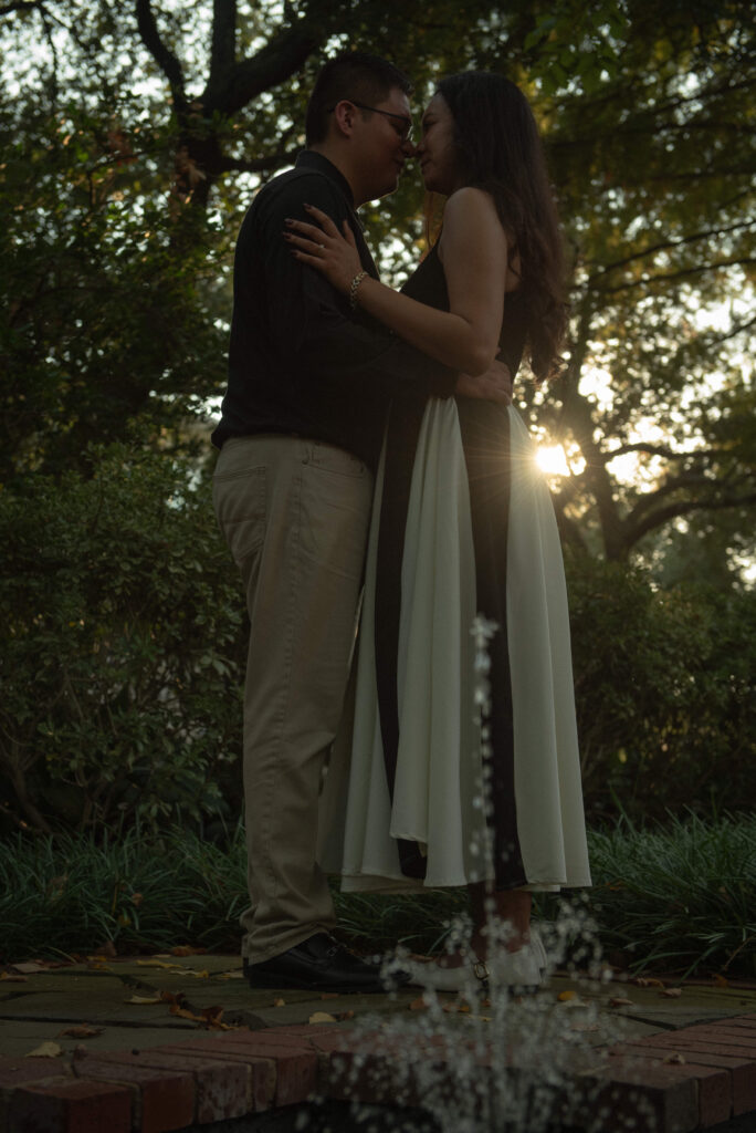 A couple standing close together with soft sunlight behind them.