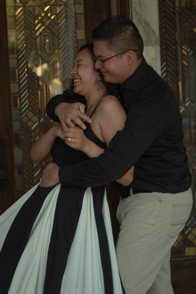 A candid photo of a woman laughing while holding onto her partner.