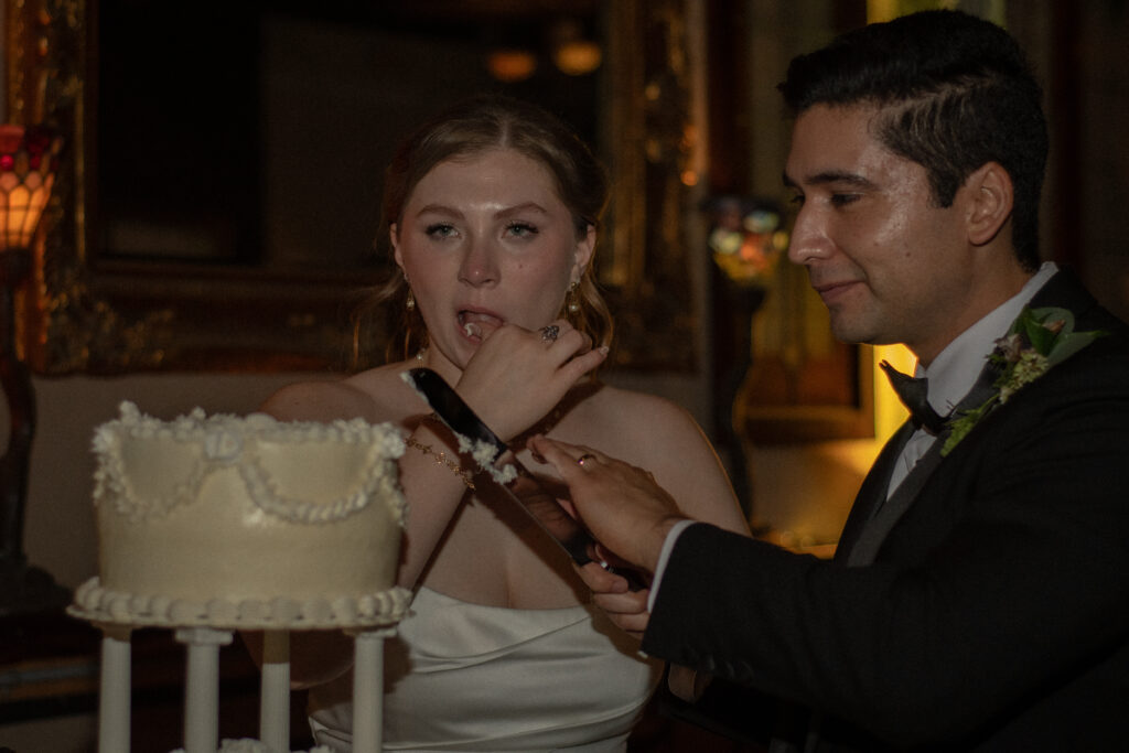 Bride playfully tastes icing while the couple cuts their wedding cake.