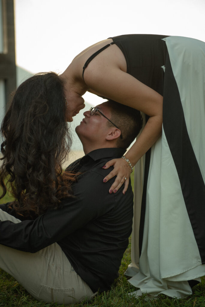A playful moment of a woman leaning toward her partner as he sits on the ground.