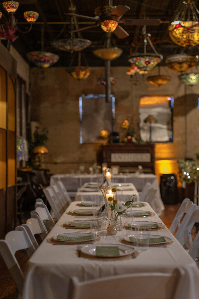 Candlelit reception tables with greenery and place settings at Nouveau Antique Art Bar.
