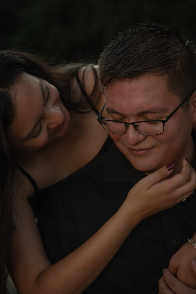 A close-up of a woman smiling as she gently holds her partner’s face.