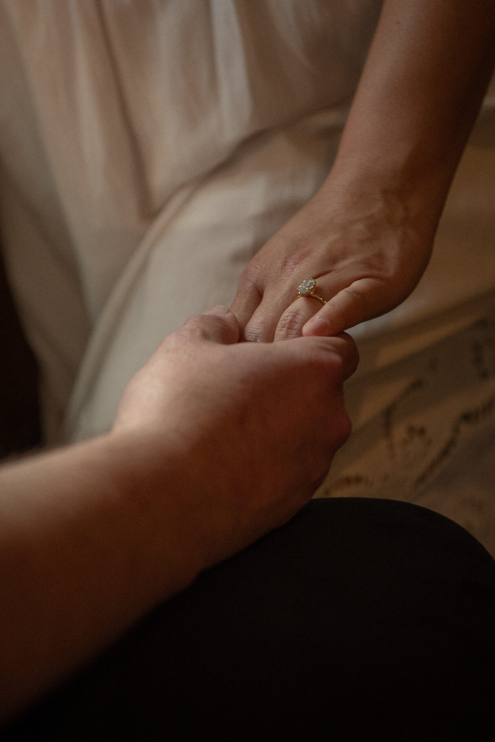 Close-up detail shot of a couple holding hands, highlighting the engagement ring during a moody dive-bar engagement photoshoot.