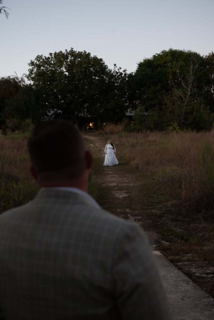 Bride standing in the distance during a first look at an outdoor Texas Hill Country elopement ceremony.