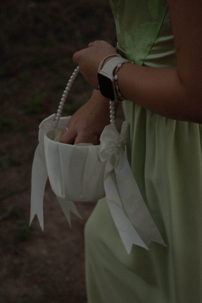 Close-up detail of a flower girl holding a basket during a Texas Hill Country outdoor wedding ceremony.