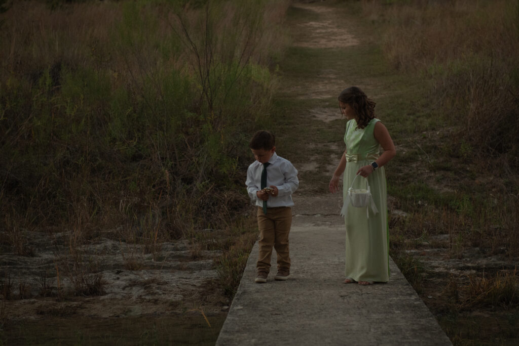 Flower girl and ring bearer walking together during an outdoor Texas Hill Country elopement ceremony.