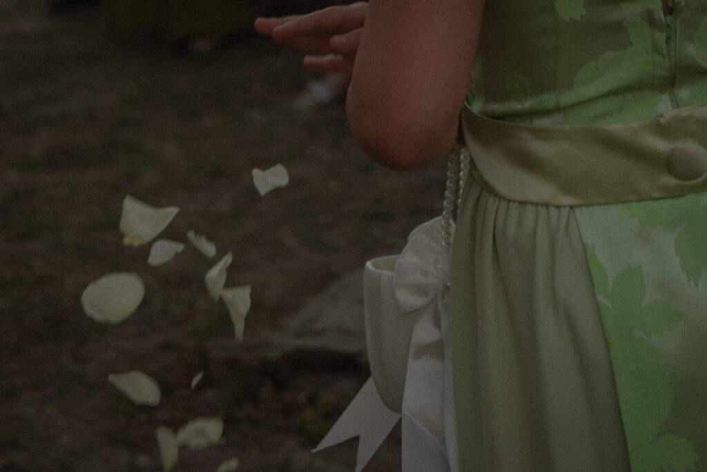 Flower petals falling during an outdoor Texas Hill Country wedding ceremony captured in a documentary style.
