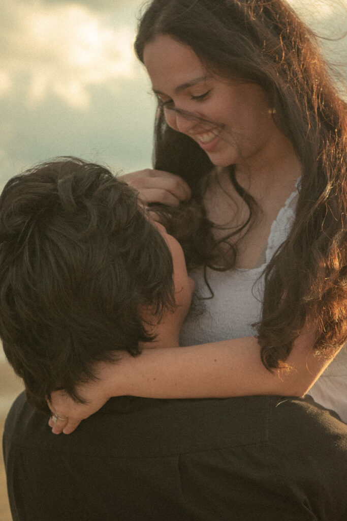 Close-up portrait of a couple smiling while sharing a romantic lift at the beach.