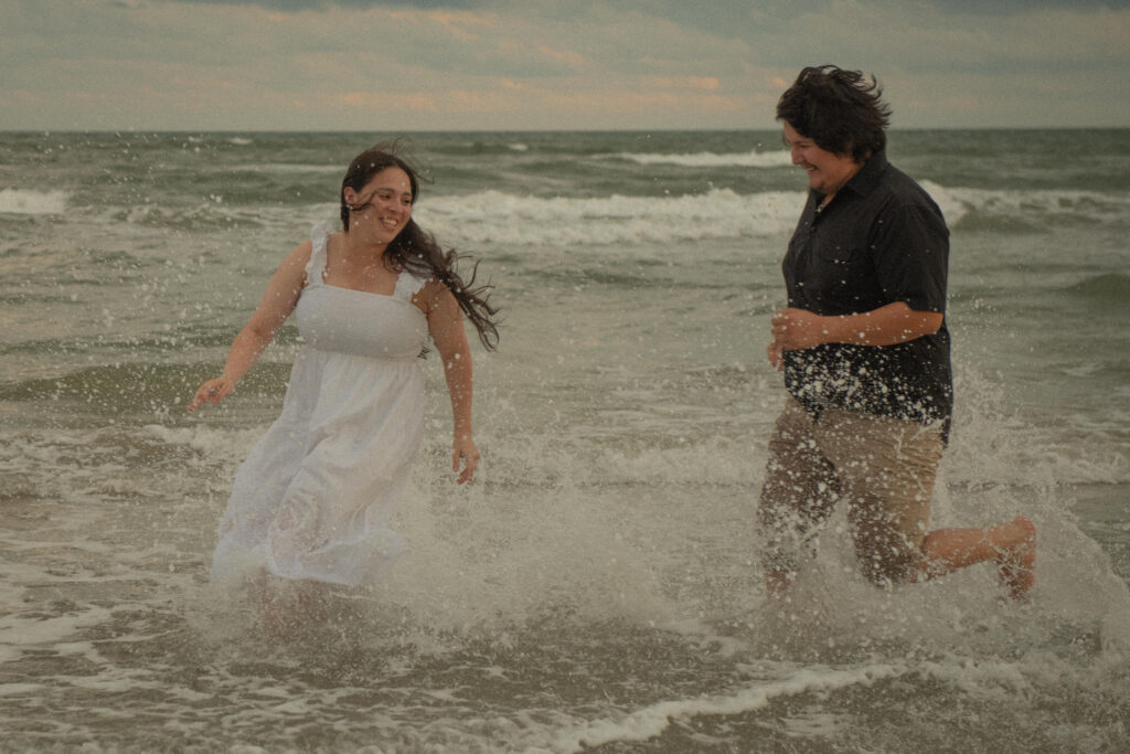 Engaged couple splashing and running through the waves at Galveston Beach.