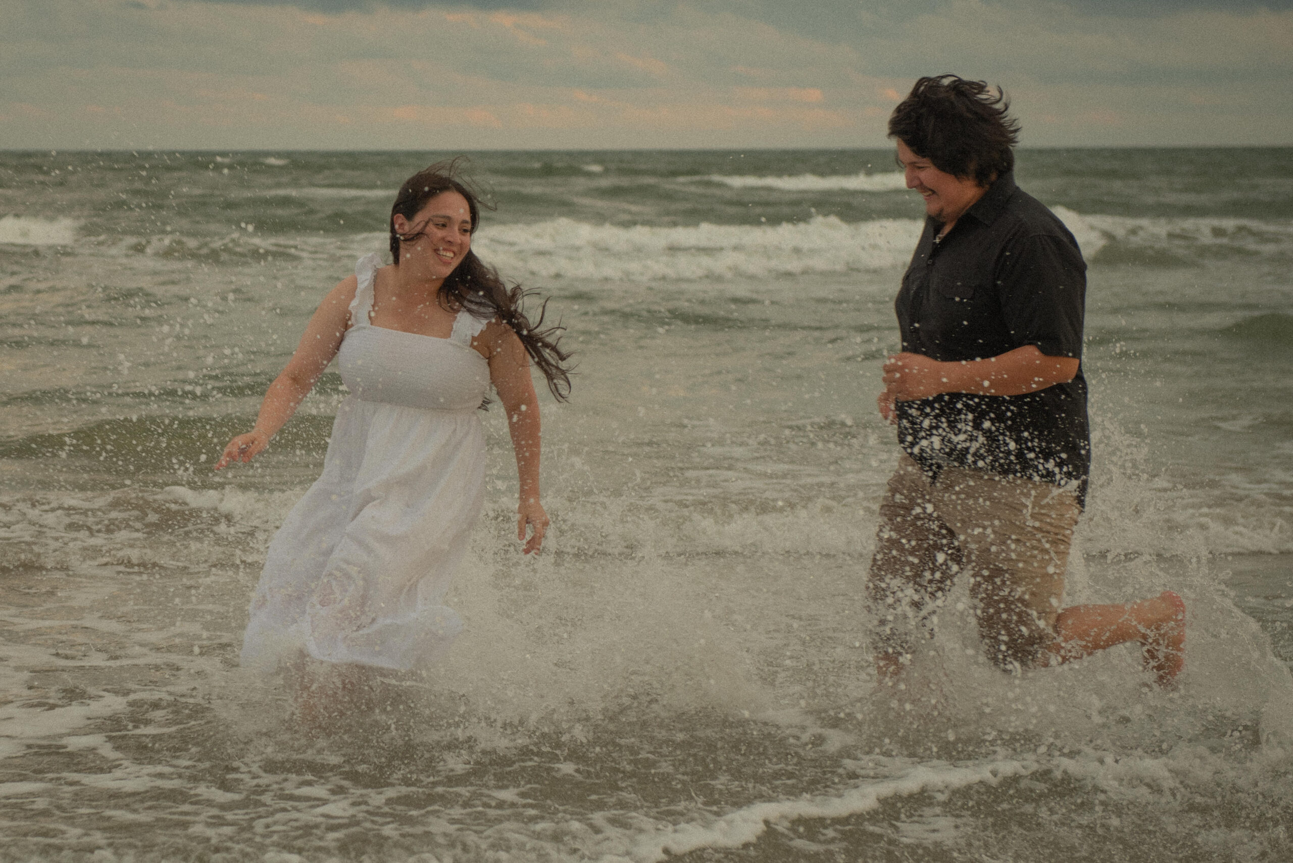 Engaged couple splashing and running through the waves at Galveston Beach.