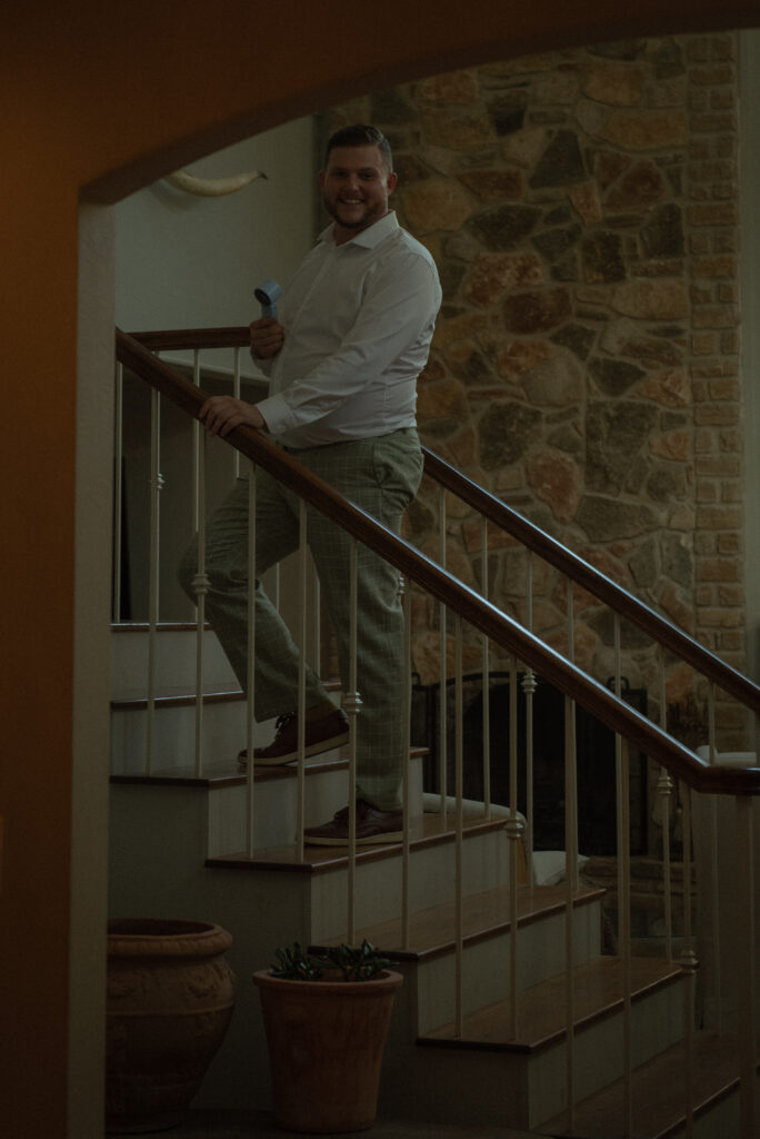 Groom getting ready on staircase inside a Texas Hill Country home during an intimate elopement day.