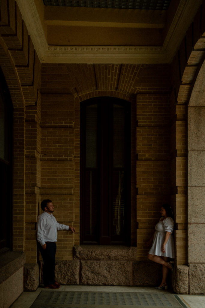 A couple sharing a candid moment in one of the shaded archways at the Houston courthouse during their elopement.
