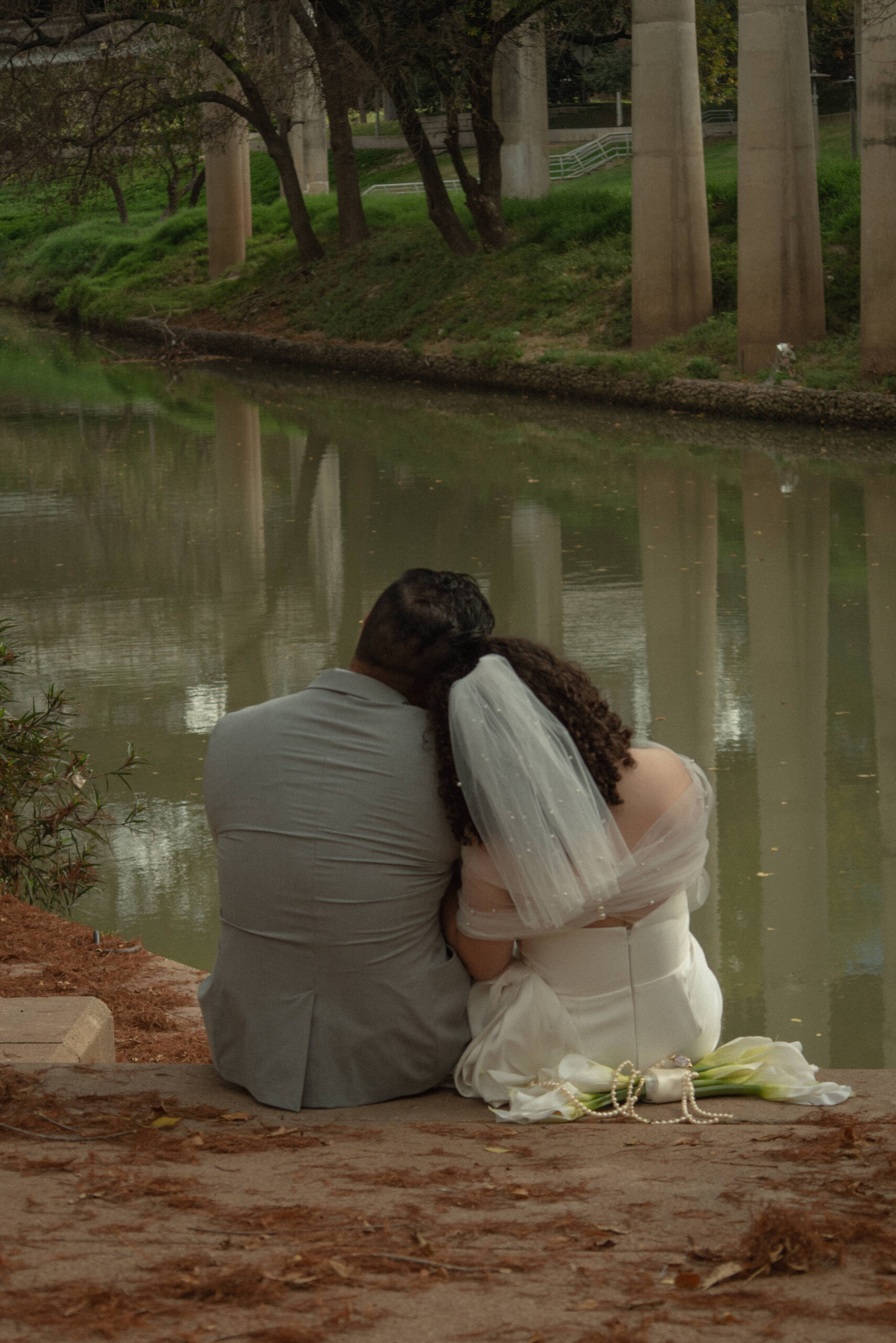 Just married couple sitting by the water after a Houston courthouse elopement at Buffalo Bayou.