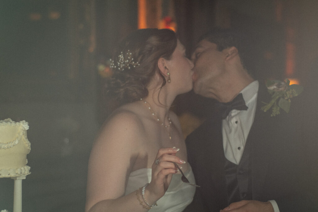 Bride and groom kiss during their cake cutting at Nouveau Antique Art Bar.