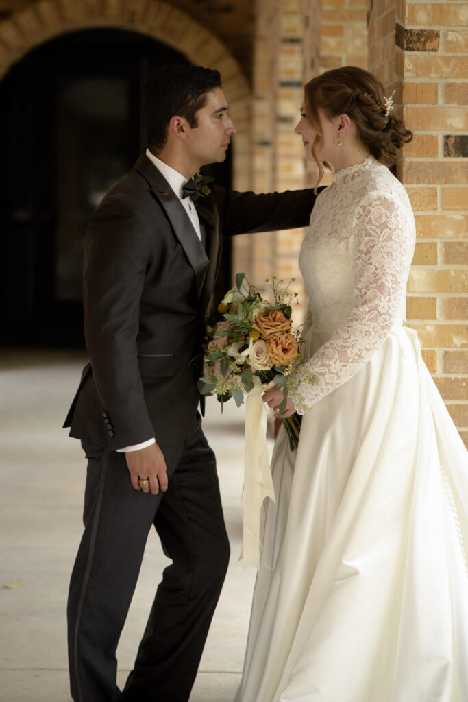 Bride and groom share a quiet moment together under the brick arches outside the church.