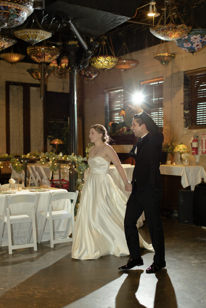 Bride and groom enter their wedding reception at Nouveau Antique Art Bar in Houston.