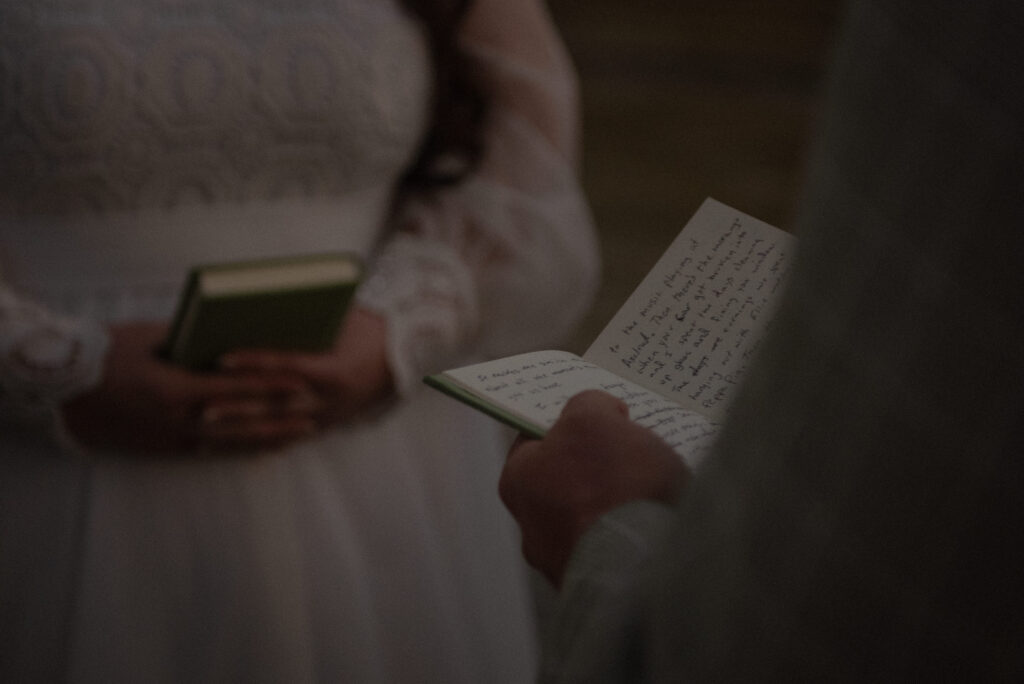 Couple holding handwritten vow books during an intimate outdoor elopement ceremony