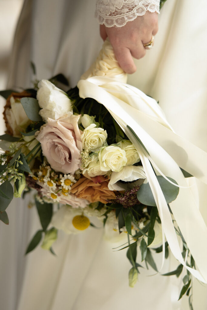 Close-up of the bride’s floral bouquet with roses, greenery, and soft neutral tones.