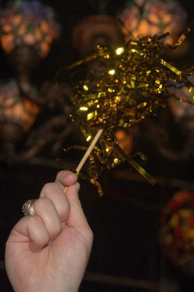 Close-up of a gold tinsel exit wand used for the couple’s wedding send-off.