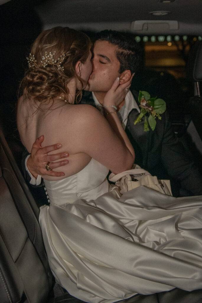Bride and groom share a kiss inside their getaway car at the end of the night