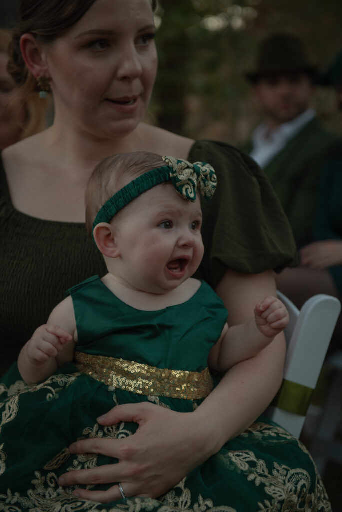 Wedding guest holding a baby during an outdoor Texas Hill Country elopement ceremony with natural candid moments.