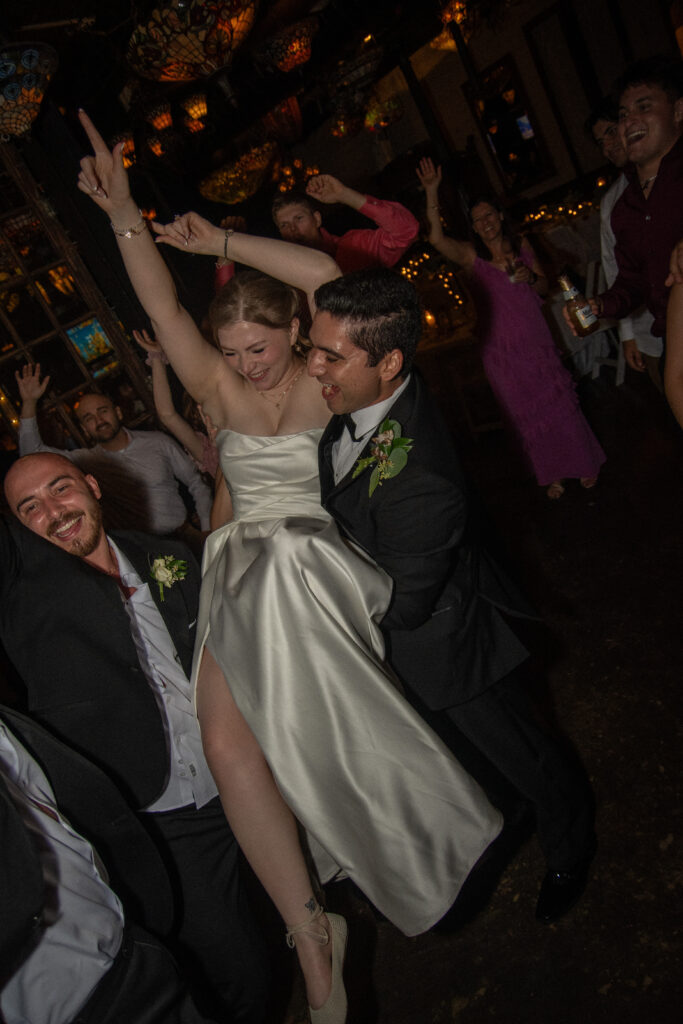 Bride is lifted into the air on the dance floor while celebrating with guests.
