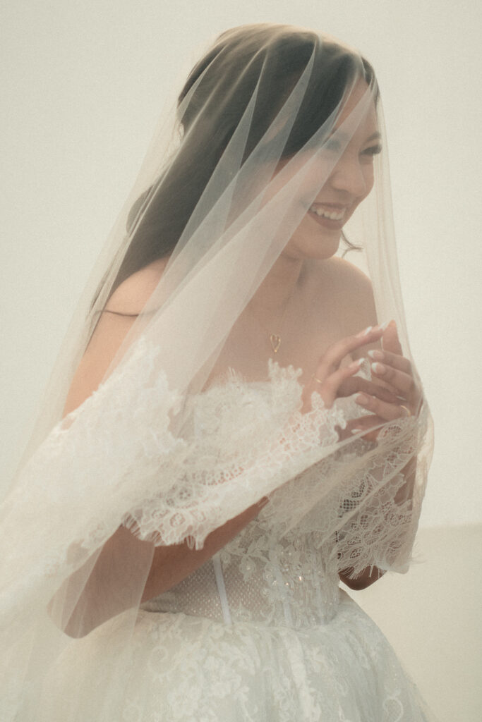 Soft bridal portrait under a wedding veil, dreamy natural light and romantic expression.