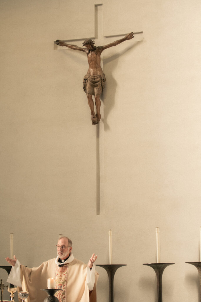 Priest officiating a Catholic wedding ceremony at the altar beneath a crucifix.