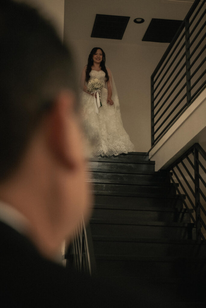 Bride holding a bouquet on a staircase during first look portraits.
