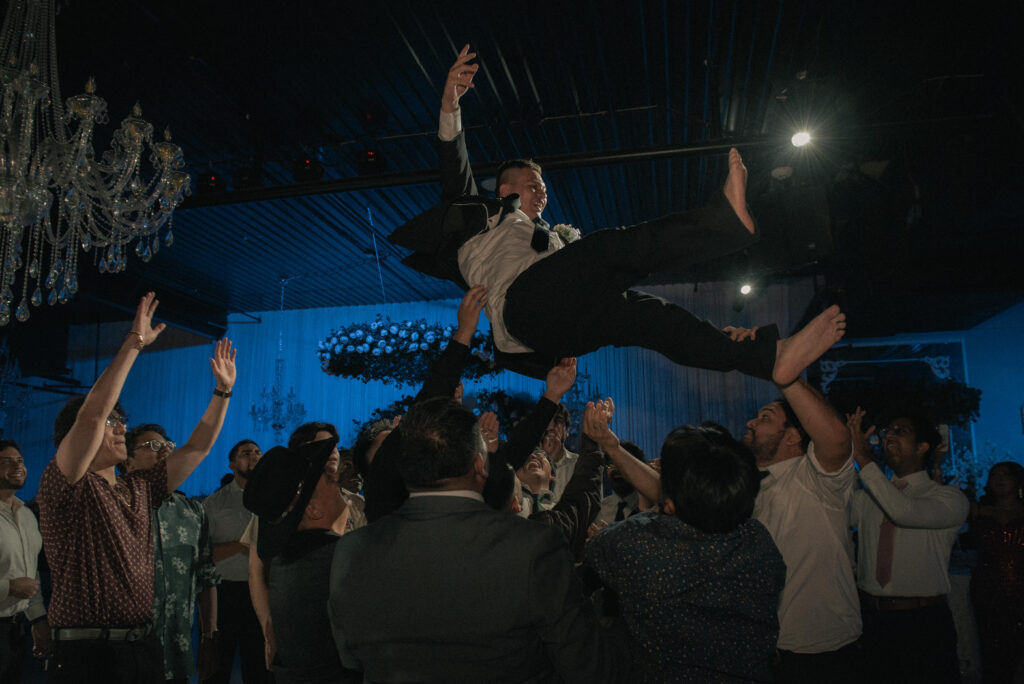Friends lifting the groom in the air during the wedding reception celebration.