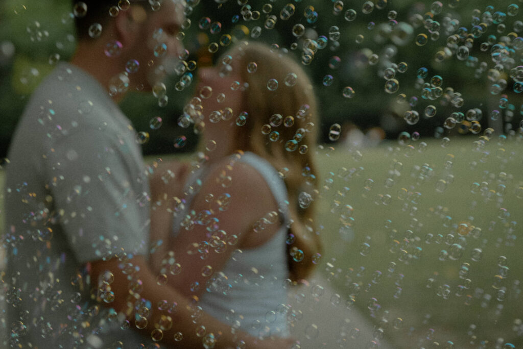 Romantic engagement photo of a couple kissing with bubbles floating in the foreground in Houston.