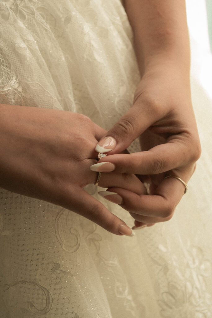 Close up of hands adjusting an engagement ring and wedding band.
