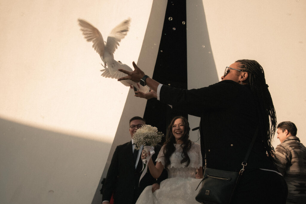 Guests celebrating with a dove release outside a wedding ceremony location.