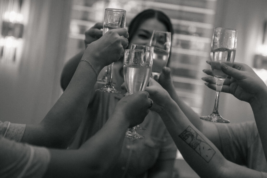 Bridesmaids clinking champagne glasses during getting ready in a documentary wedding moment.