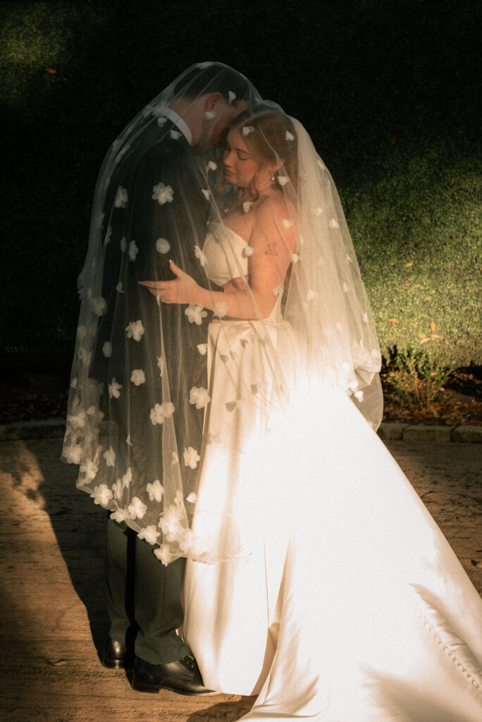 Romantic couple portrait under the veil with soft light and an intimate wedding moment.