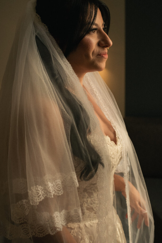 Bridal portrait in veil with soft window light and a calm expression.