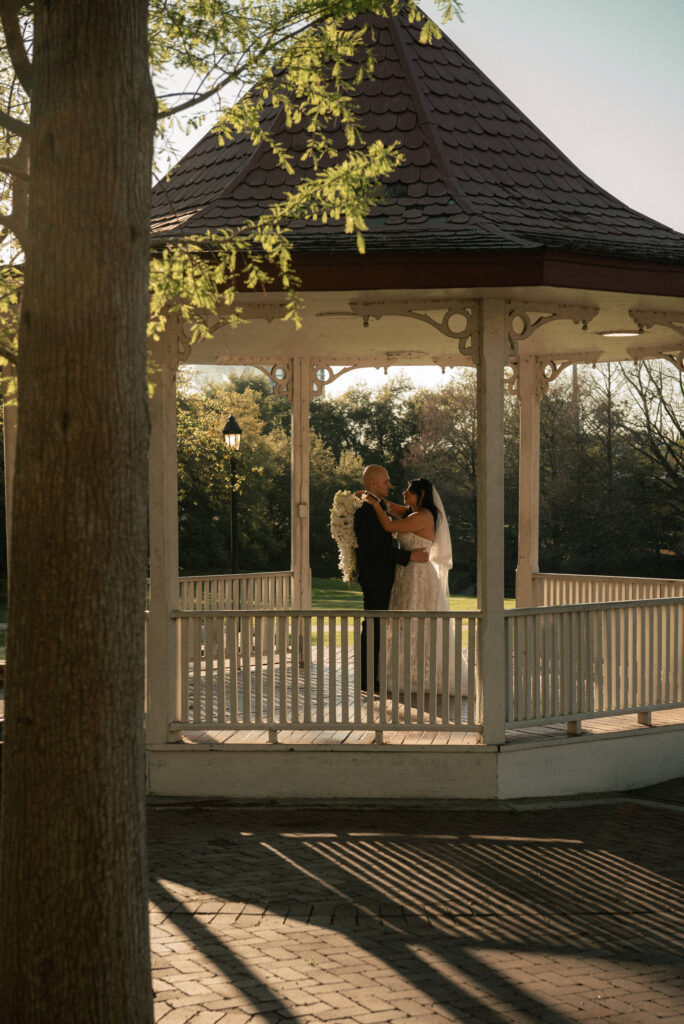 Couple portrait in a gazebo during golden hour wedding photos outdoors.