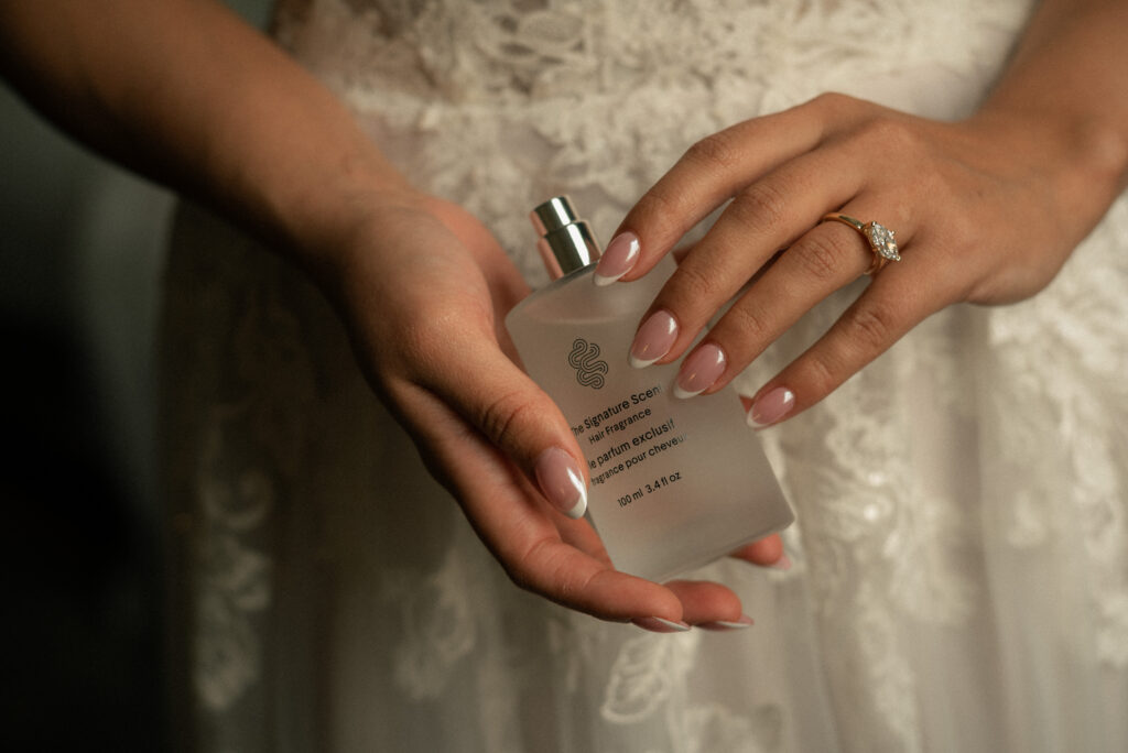 Close-up of perfume bottle and engagement ring for wedding detail photography.