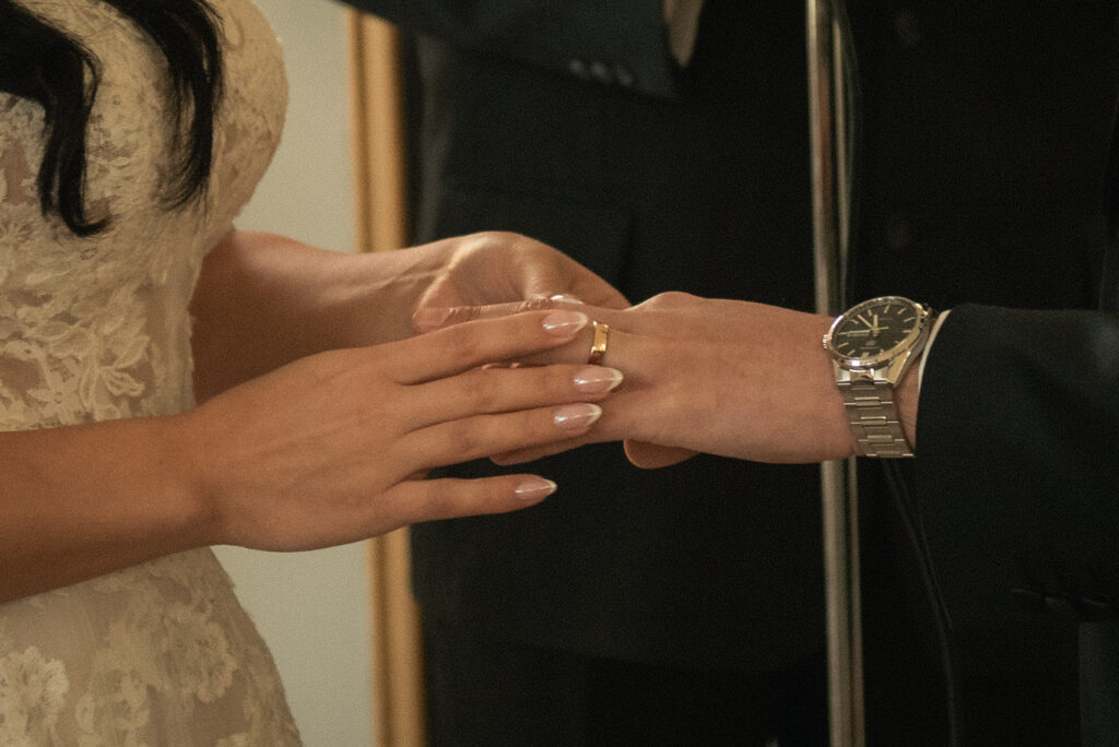Close-up of ring exchange during the ceremony with hands and wedding details.