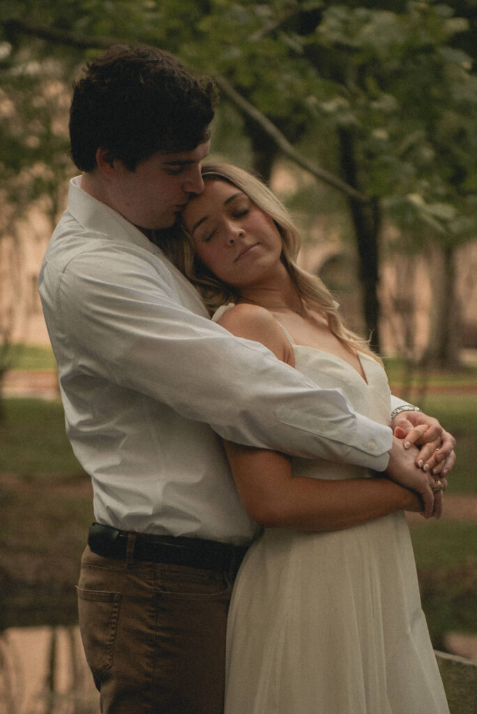 Couple embracing in soft light during a wooded park engagement session in Houston.