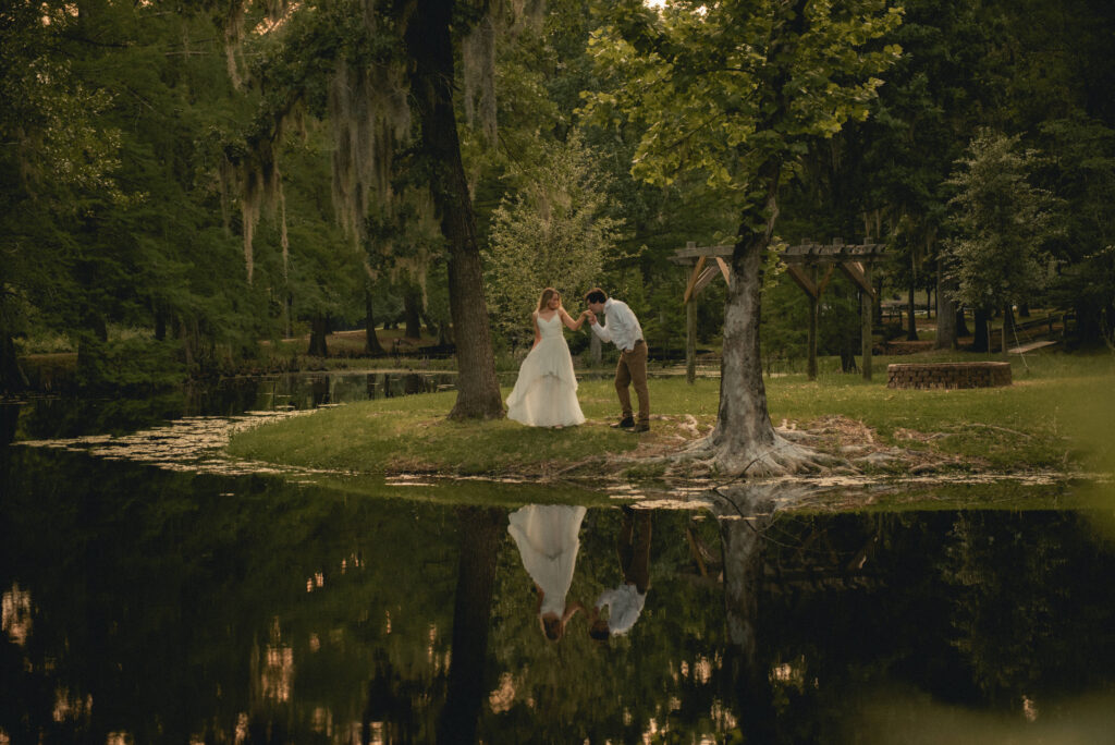 Engaged couple sharing a hand kiss beside a pond during a Houston engagement session.
