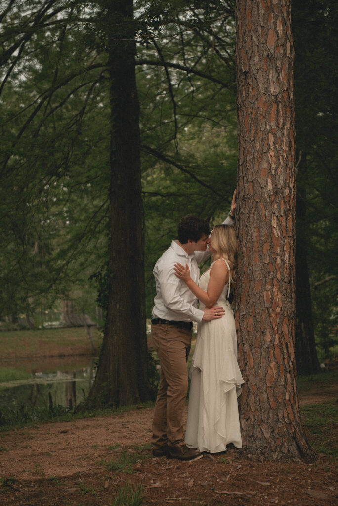 Engaged couple kissing beside a large tree during a Houston park engagement session.