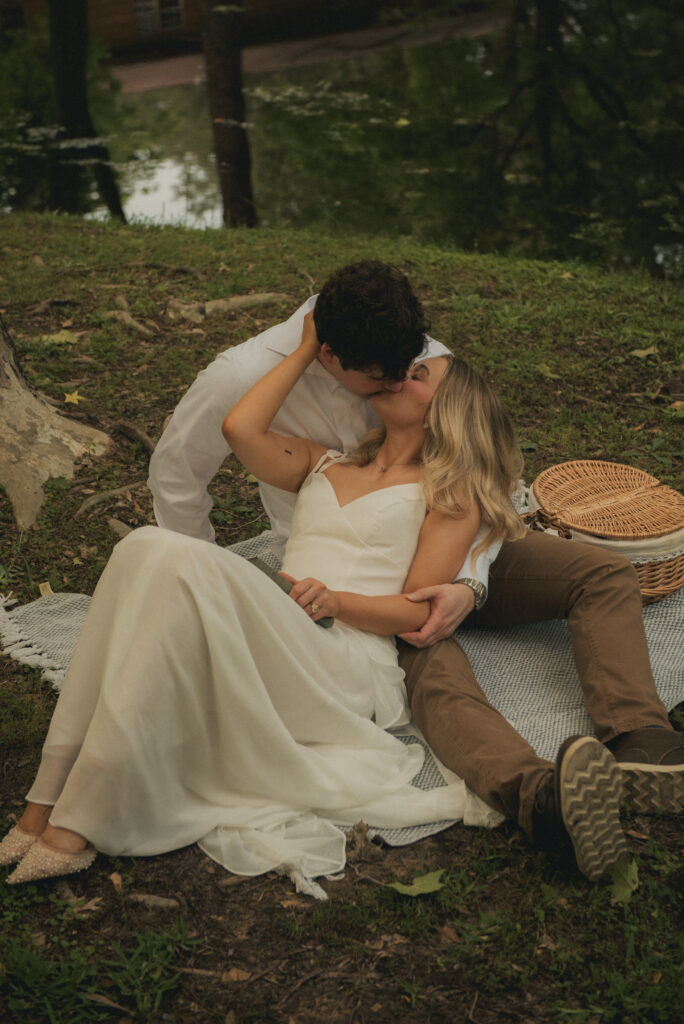 Engaged couple kissing on a picnic blanket during a nature engagement session in Houston.